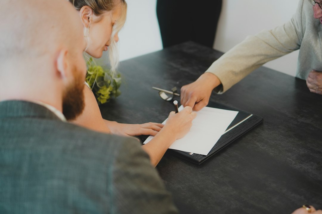 Personen unterschreiben einen Immobilienkaufvertrag am Schreibtisch