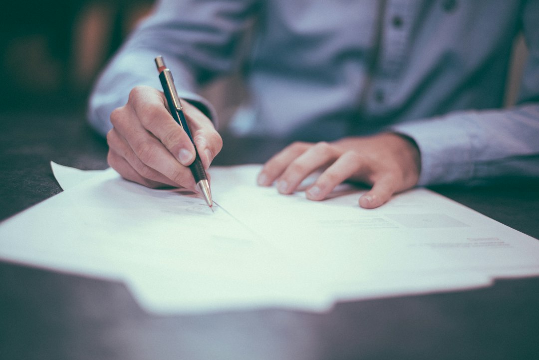 Unterlagen und Stift auf einem Schreibtisch als Symbol für die Prüfung eines Immobilienkaufvertrags